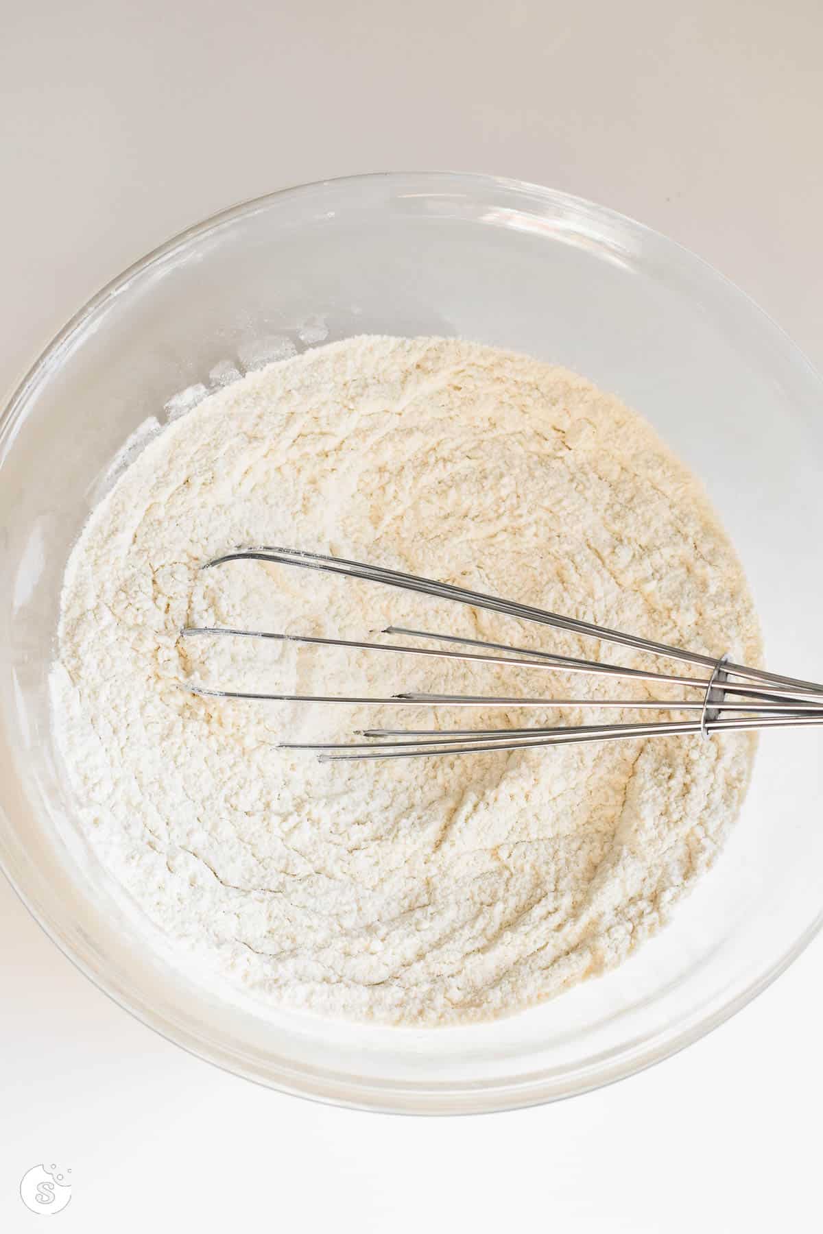 Dry ingredients in a clear bowl with a metal whisk