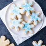 Snowflake-shaped sugar cookies with white icing and blue sprinkles